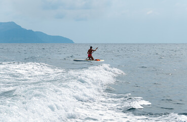 Fototapeta na wymiar The girl floats on the sea on a sup board.
