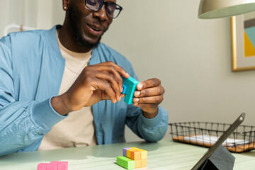 Black man making wooden geometric puzzle in office