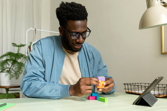 Black man making wooden geometric puzzle at work