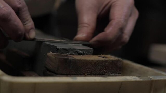 Master swordsmith is sharpening knife on grindstone with water