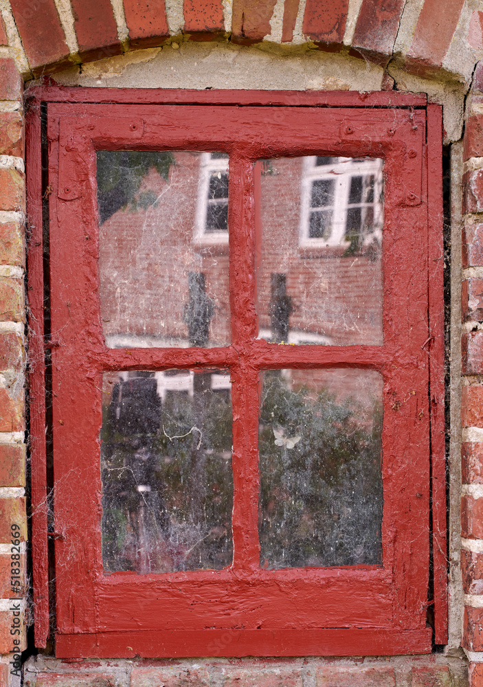Poster closeup of an old dirty window in a red brick home. zoom in on casement with red wood frame on a his