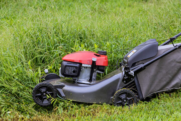 Fototapeta na wymiar Gardening activity in lawn mower working on a green lawn with grass being cutting