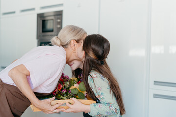 Granddaughter kissing her grandma in kitchen