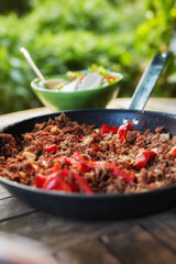 Close up view of hot juicy ground beef stewed with tomato sauce, spices, basil and finely chopped vegetables in a frying pan, classic recipe. Delicious meal prepared in a restaurant or home kitchen