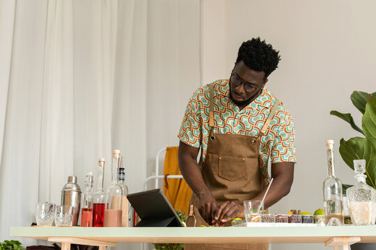 Male cocktail expert looking at tutorials on tablet