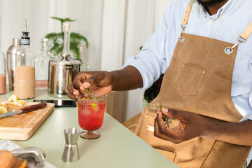 Cropped mixologist adding rosemary to cocktail