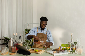 Handsome African preparing cocktails from home