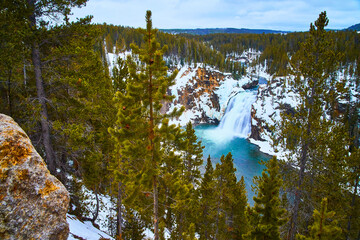 Yellowstone in winter at stunning lower falls through pine trees
