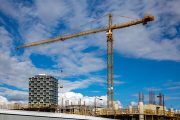 New construction of high-rise buildings in Burnaby city, industrial construction site, construction equipment,  construction crane on the background of finished skyscrapers and a  blue cloudy sky