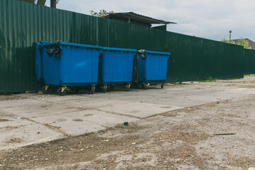 Garbage containers near the green fence