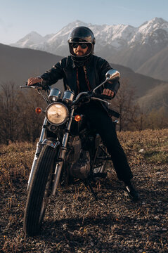 Male biker riding motorcycle near mountains