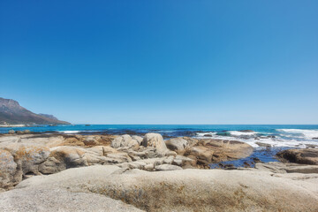 Copy space ocean view of beach with rocks, boulders and sea water washing onto rocky shore on peaceful summer vacation. Rough texture and detail of scenic coastline in tropical island resort overseas