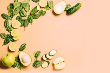Green fresh fruits and vegetables, spinach, apple, lime, avocado, cucumber light brown background