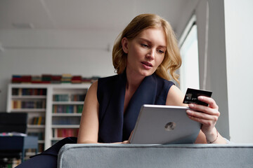 Smiling businesswoman making online payment on tablet