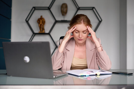 Tired businesswoman at table with laptop