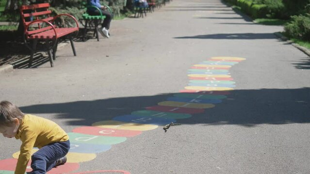 Funny little child running on colorful alphabet letters drawn on asphalt