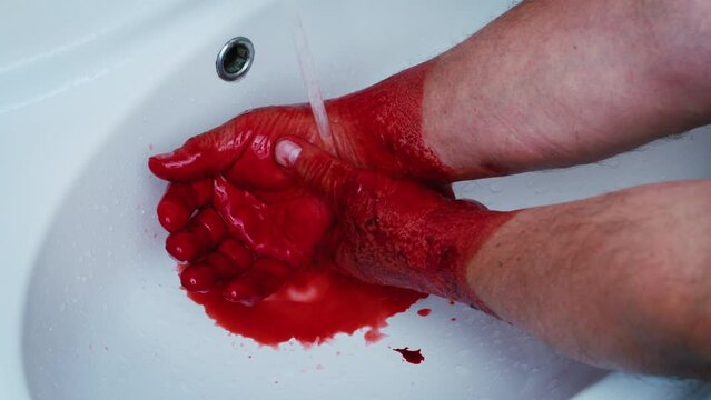 Faceless man washing hands from red liquid, paint, blood or berries under tap in sink. Male dirty arms under running water in bathroom. Butcher, worker of slaughterhouse, stockyard, butchery, killer