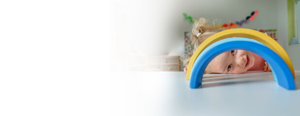 Toddler girl playing with wooden rainbow indoors