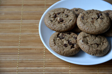 Delicious oatmeal cookies with chocolate chips on a white plate on a mat. Sweet oatmeal cookies close-up.