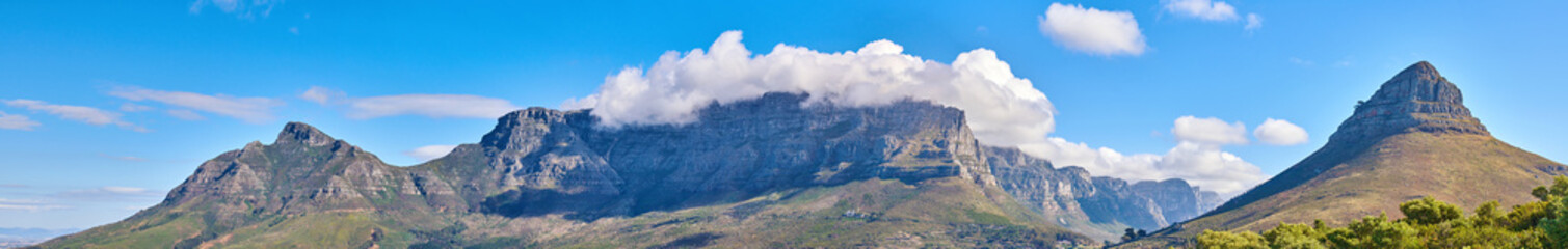 Panoramic landscape of the majestic Table Mountain and Lions Head in Cape Town, Western Cape. A cloudscape sky with copy space over large mountainous and hilly terrain in peaceful nature