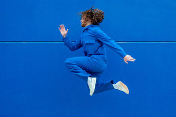 Man in blue clothes jumping against wall