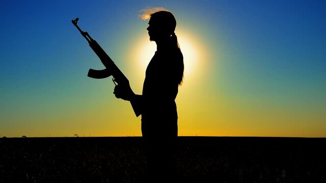 Ukraine War. A young man with a Kalashnikov assault rifle trains in the field. Silhouette of a man with a Kalashnikov assault rifle. The concept of war, terrorism, aggression against Ukraine.