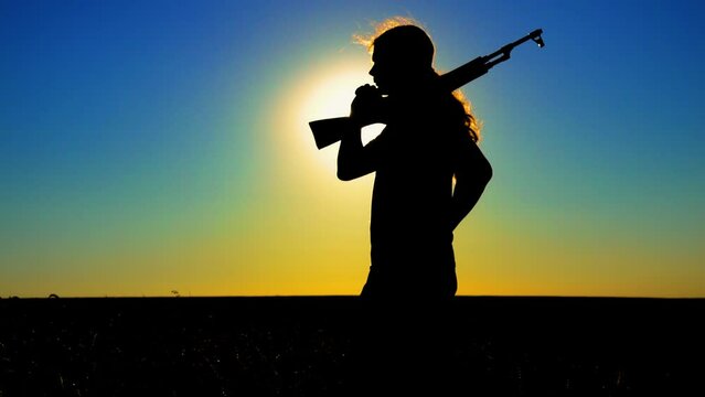 Ukraine War. A young man with a Kalashnikov assault rifle trains in the field. Silhouette of a man with a Kalashnikov assault rifle. The concept of war, terrorism, aggression against Ukraine.
