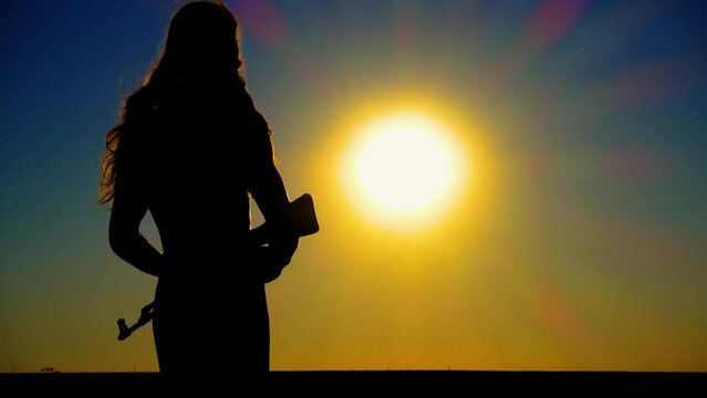 The problem of sexism. A young boy-girl with a Kalashnikov assault rifle at sunset. A transgender man with a Kalashnikov in a field at dawn. The concept of justice, equality, sexual minorities, LGBT.