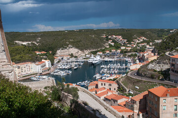 Naklejka na ściany i meble Harbor and waterfront with ships and yachts moored at sea in the town of Bonifacio on the island of Corsica in France.