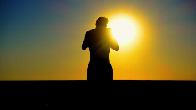 Ukraine War. A young man with a Kalashnikov assault rifle trains in the field. Silhouette of a man with a Kalashnikov assault rifle. The concept of war, terrorism, aggression against Ukraine.