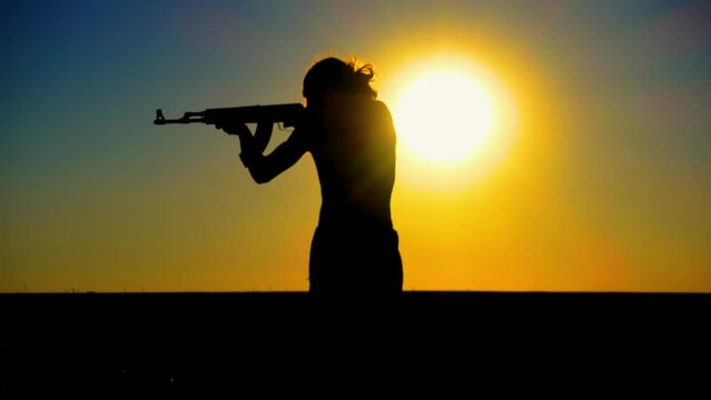 Ukraine War. A young man with a Kalashnikov assault rifle trains in the field. Silhouette of a man with a Kalashnikov assault rifle. The concept of war, terrorism, aggression against Ukraine.