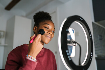 Glad black vlogger recording beauty video on smartphone