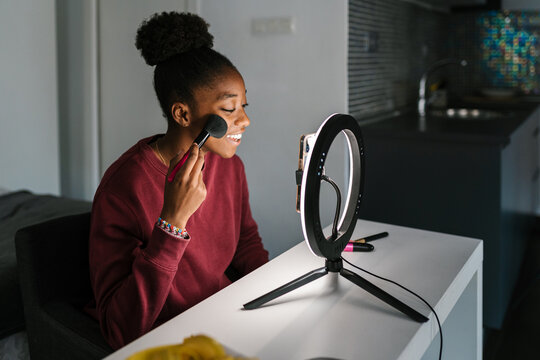 Black blogger recording makeup tutorial on smartphone