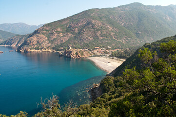 View of the sea with sandy beach and the mountains of the typical landscape on the island of Corsica
