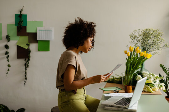 Cool woman with curly hair working at floral studio