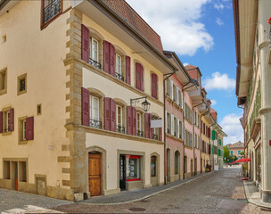 Fototapeta na wymiar Street view of old buildings in a historic city with built medieval architecture and a cloudy blue sky in Annecy, France. Beautiful landscape of an empty small urban town with homes or houses