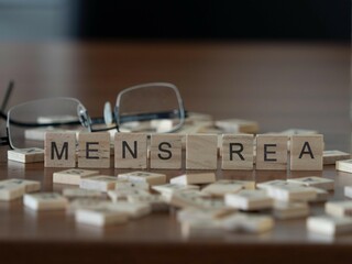 mens rea word or concept represented by wooden letter tiles on a wooden table with glasses and a...