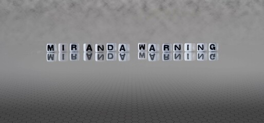 miranda warning word or concept represented by black and white letter cubes on a grey horizon...