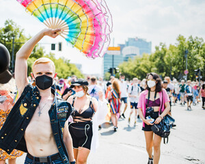 Man walking holding big ruffled rainbow handheld fan during Pride