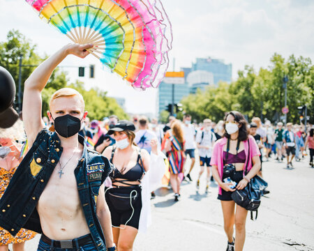 Man walking holding big ruffled rainbow handheld fan during Pride