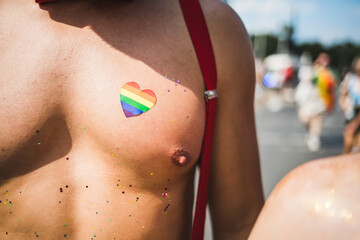 Close up of a rainbow heart sticker on a fit male's chest
