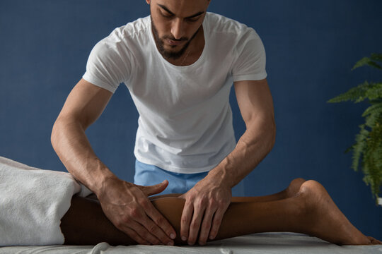 Massage therapist kneading calf of barefoot client