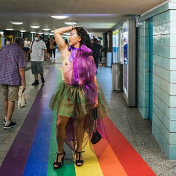 Asian man in rainbow coloured chiffon dress standing on rainbow floor