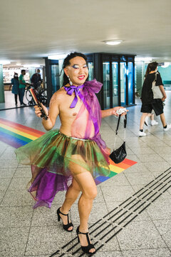 Happy asian man in a rainbow chiffon dress walking in underground