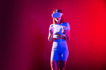 Video Gaming Concept. women playing with virtual reality goggles, VR headset, modern technology glasses  with neon light  on a colored background