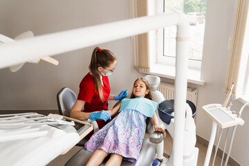 Pediatric dentist and cheerful girl child smiling in dentistry. The child smiles at the consultation with the dentist.