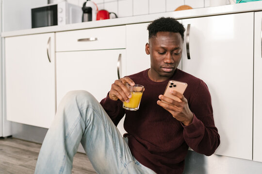 Black man with juice browsing cellphone
