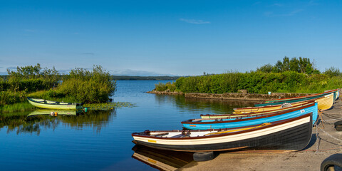 Fototapeta na wymiar warm evening light at Lough Melvin light with colorful wooden fishing boats in the foreground