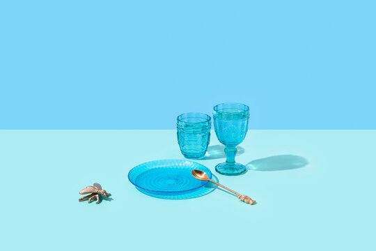 Composition of blue glasses, plate, spoon and decorative fly