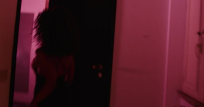 back view of young scared woman running in the corridor from her violent husband